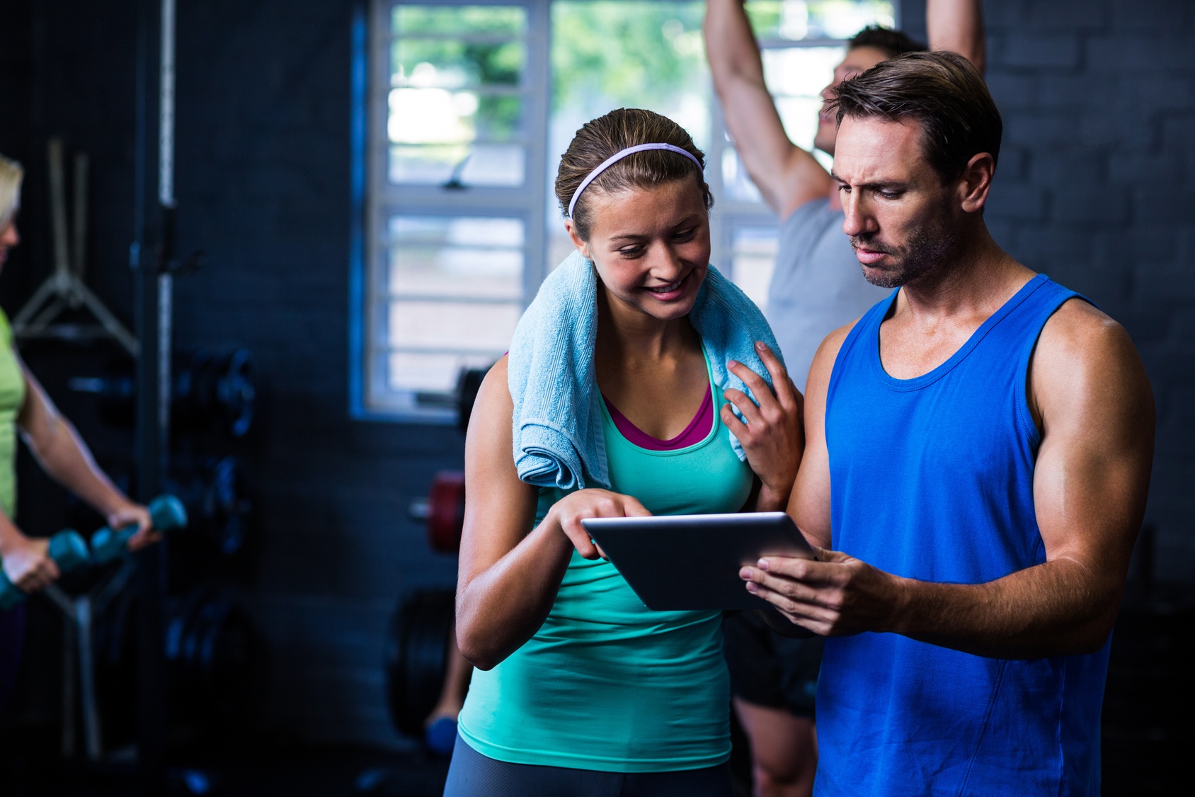 Athletes looking in tablet computer at gym